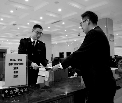 昨天，货代公司工作人员向青岛大港海关工作人员递交《中韩自贸协定》正式生效后中国首票进口货物报关单。 新华社发