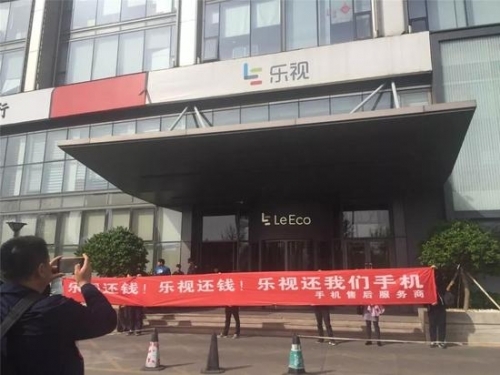 ▲4月11日，讨债者唐堂和同伴拉出乐视还钱的条幅，但又迅速收了起来。